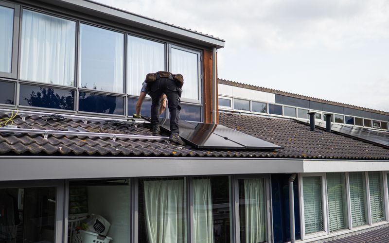Monteur bringt Solarmodule auf einem Wohnhausdach an