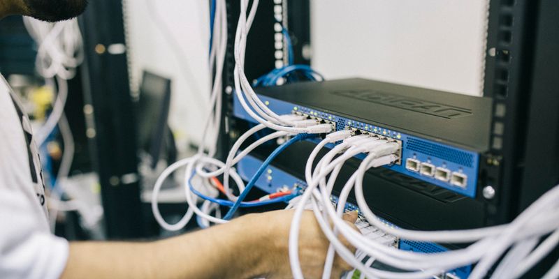 Techniker steckt Netzwerkkabel an einem Router im Verteilerschrank